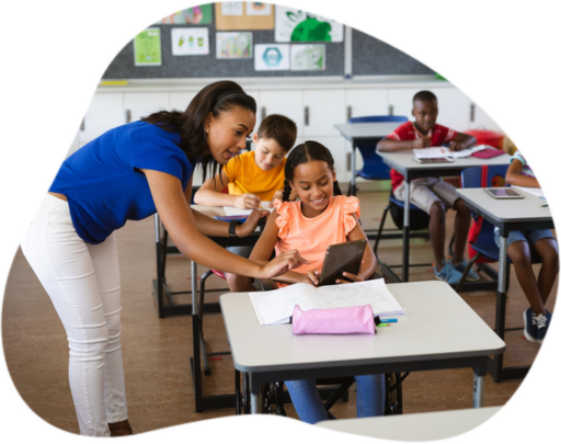Professora aponta para tablet que esta na mão de aluna, em uma sala de aula com alunos diversos.