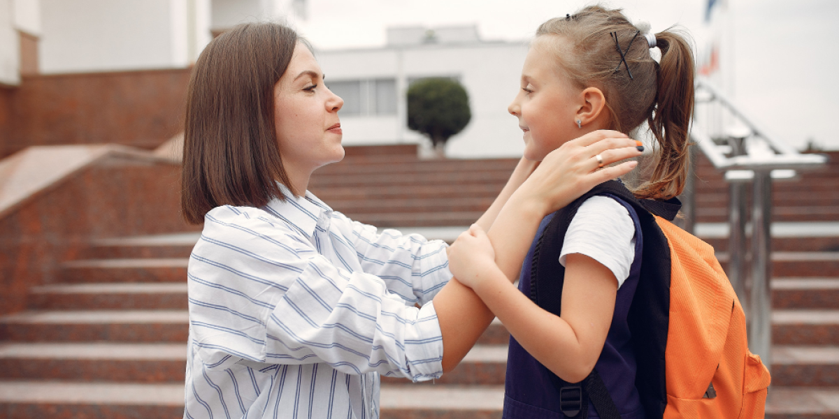 mãe preparando sua filha pequena para a escola.