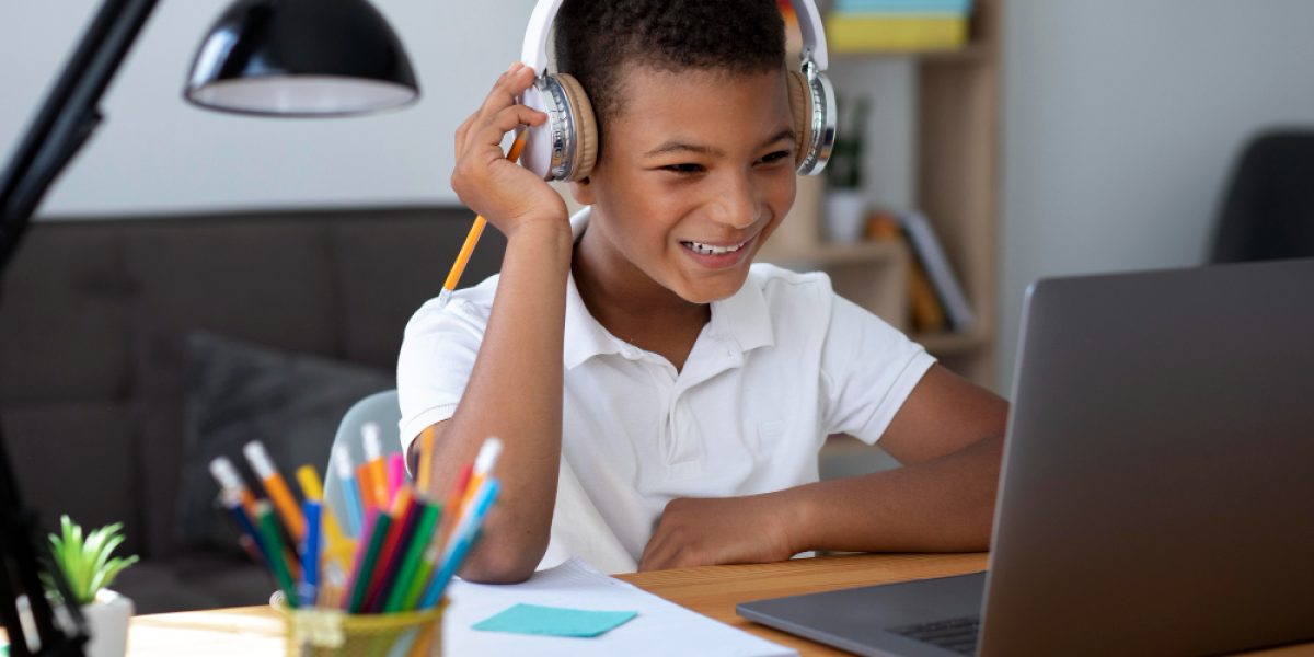 menino sorridente assistindo aula online com fones de ouvido